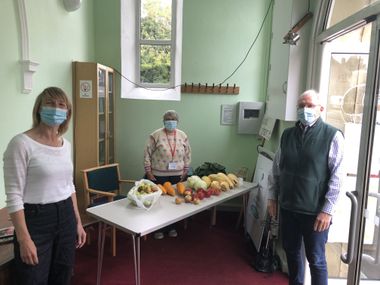 Three volunteers wearing masks stood around a table of donated vegetables in Peasedown St John