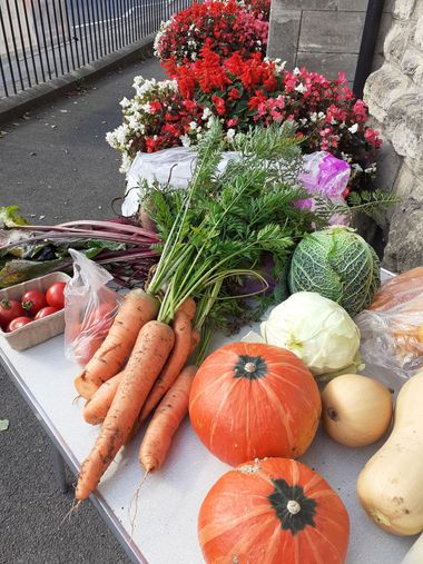 A table outside full of donated vegetables at Peasedown St John, including carrots, squash, tomatoes, chard and cabbage.